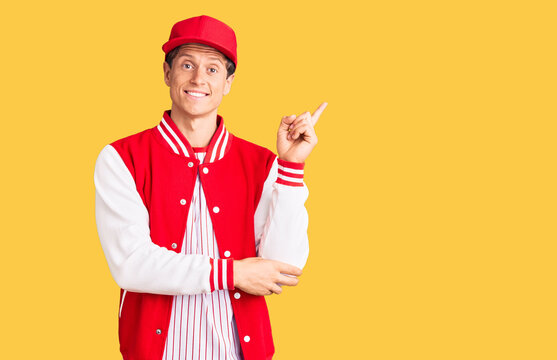 Young handsome man wearing baseball uniform smiling happy pointing with hand and finger to the side