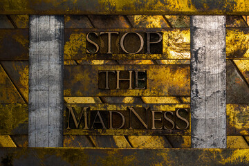 Stop The Madness text formed with real authentic typeset letters on vintage textured silver grunge copper and gold background
