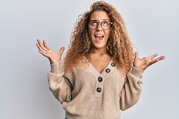 Beautiful caucasian teenager girl wearing casual clothes and glasses crazy and mad shouting and yelling with aggressive expression and arms raised. frustration concept.