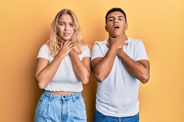 Young interracial couple wearing casual white tshirt shouting and suffocate because painful strangle. health problem. asphyxiate and suicide concept.