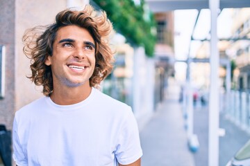 Fototapeta premium Young handsome hispanic man smiling happy walking at street of city