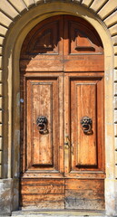 Hauseingang mit Rundbogen und antiker Holztür mit Löwenkopfklopfern