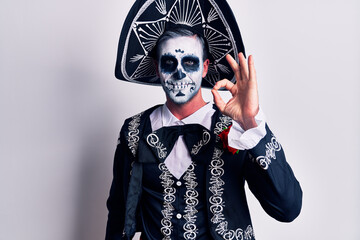 Young man wearing mexican day of the dead costume over white smiling positive doing ok sign with hand and fingers. successful expression.