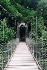 Inside view of the Holtzarte suspension bridge with wooden floor and lush forest in the background