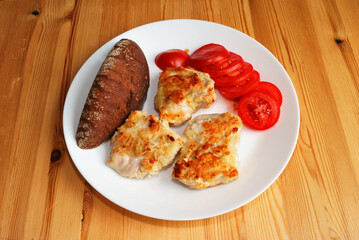 Fried chicken fillet with tomatoes and bread.