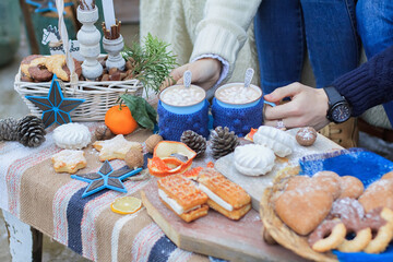 Winter decor sweet table. Mugs with cocoa. People hands