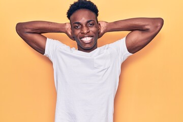 Fototapeta na wymiar Young african american man wearing casual clothes relaxing and stretching, arms and hands behind head and neck smiling happy