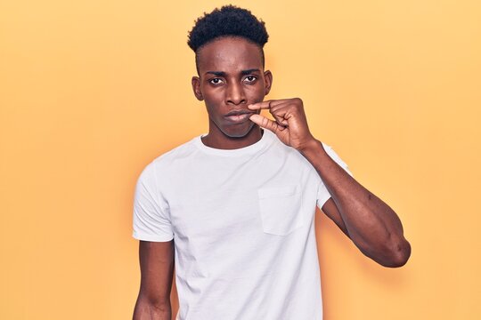 Young african american man wearing casual clothes mouth and lips shut as zip with fingers. secret and silent, taboo talking