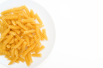 Raw uncoocked pasta fusilli in white ceramic plate isolated on white, italian cousine concept