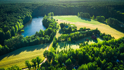 Winding river between green forests and fields at sunrise