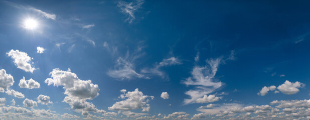 Naklejka na ściany i meble White cumulus clouds and sun in blue sunshiny sky panoramic high resolution background