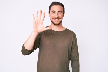 Young handsome man wearing casual clothes showing and pointing up with fingers number five while smiling confident and happy.
