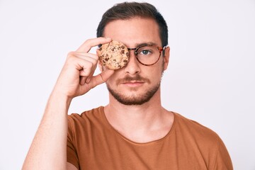 Young handsome man holding cookie thinking attitude and sober expression looking self confident