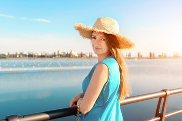 Close-up portrait of smiling caucasian woman in blue dress and straw hat while relaxing on holiday. Lifestyle