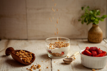 Delicious Strawberry parfait on a wooden background with falling granola