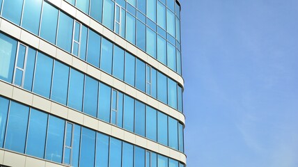 Blue curtain wall made of toned glass and steel constructions under blue sky. A fragment of a building.
