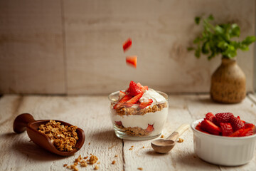 Delicious Strawberry parfait on a wooden background with falling strawberries
