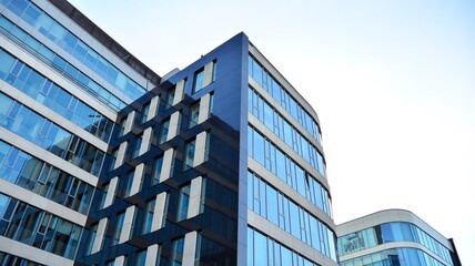 Blue curtain wall made of toned glass and steel constructions under blue sky. A fragment of a...