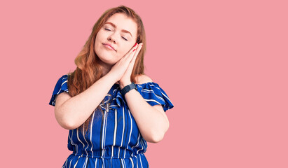 Young beautiful redhead woman wearing casual clothes sleeping tired dreaming and posing with hands together while smiling with closed eyes.