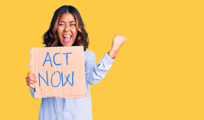 Young beautiful mixed race woman holding act now banner screaming proud, celebrating victory and...