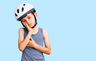 Little cute boy kid wearing bike helmet thinking looking tired and bored with depression problems with crossed arms.