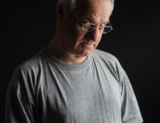 Obraz premium Mature man with experienced and knowing face expression. Studio shot with black background.