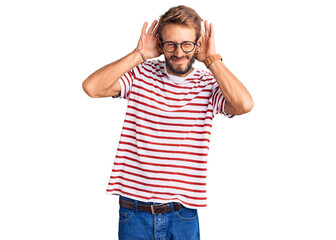 Fototapeta premium Handsome blond man with beard wearing casual clothes and glasses trying to hear both hands on ear gesture, curious for gossip. hearing problem, deaf