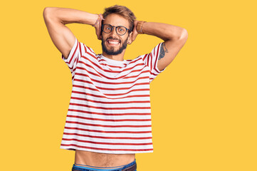 Handsome blond man with beard wearing casual clothes and glasses crazy and scared with hands on head, afraid and surprised of shock with open mouth