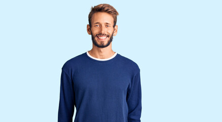 Handsome blond man with beard wearing casual sweater with a happy and cool smile on face. lucky person.