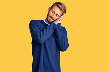 Handsome blond man with beard wearing casual sweater sleeping tired dreaming and posing with hands together while smiling with closed eyes.