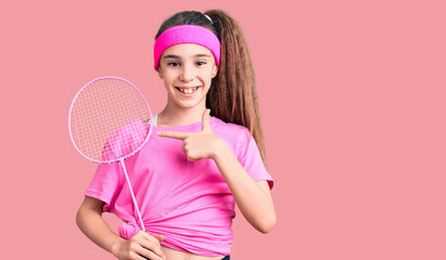 Obraz na płótnie Canvas Cute hispanic child girl holding badminton racket smiling happy pointing with hand and finger