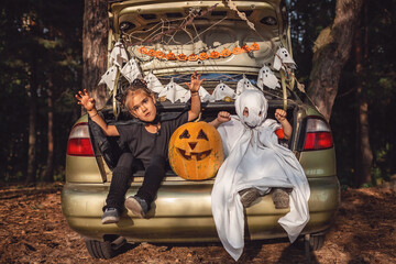 Safe distant Halloween celebration. Kids preparing decoration for party in the trunk of car