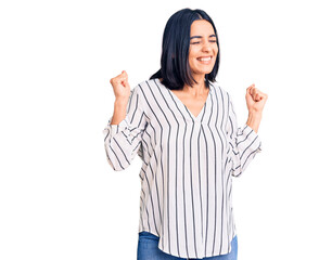 Young beautiful latin woman wearing casual clothes very happy and excited doing winner gesture with arms raised, smiling and screaming for success. celebration concept.