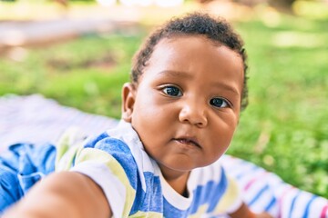 Adorable african american toddler sitting on the grass at the park.