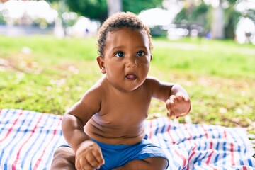 Adorable african american toddler sitting on the grass at the park.