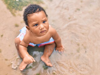 Adorable african american toddler sitting at the beach.
