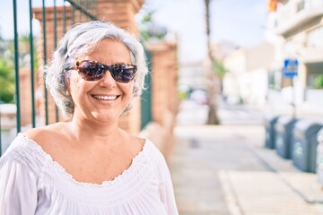 Middle age woman with grey hair smiling happy outdoors