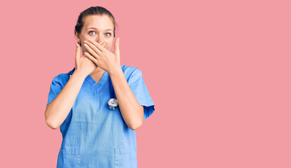 Young beautiful blonde woman wearing doctor uniform and stethoscope shocked covering mouth with hands for mistake. secret concept.