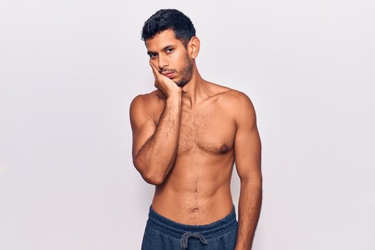 Young latin man standing shirtless thinking looking tired and bored with depression problems with crossed arms.
