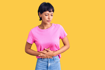 Young brunette woman with short hair wearing casual clothes with hand on stomach because indigestion, painful illness feeling unwell. ache concept.