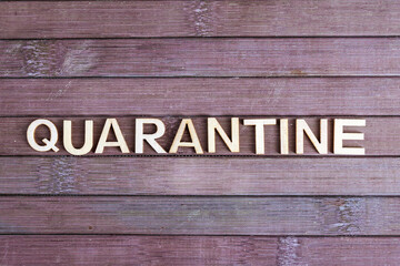 Quarantine - word made from wooden letters, not wooden background. Isolation to prevent infection. Quarantine concept.