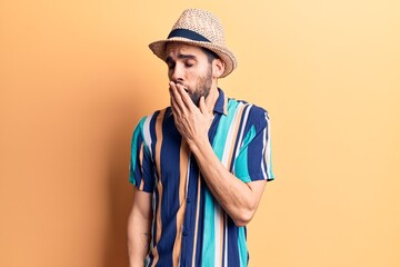 Young handsome man with beard wearing summer hat and shirt bored yawning tired covering mouth with hand. restless and sleepiness.