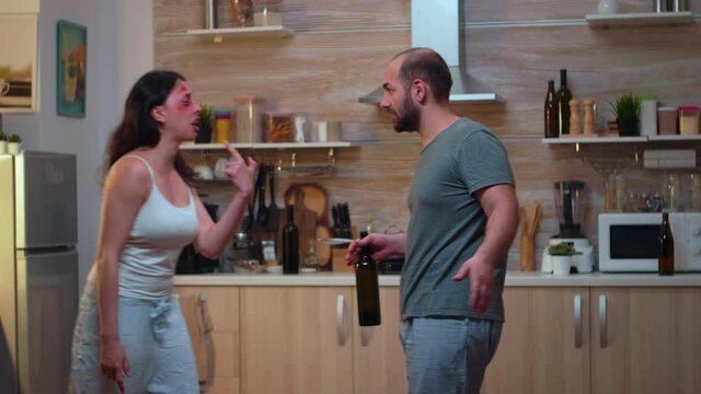 Abused wife fighting with drunk furious husband. Terrified beaten woman covered in bruises suffering injury from alcoholic violent brutal aggressive man screeming and hitting.