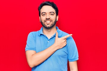 Young hispanic man wearing casual clothes smiling cheerful pointing with hand and finger up to the side