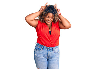 Young african american plus size woman wearing casual style with sleeveless shirt posing funny and crazy with fingers on head as bunny ears, smiling cheerful