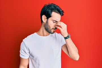 Young hispanic man wearing casual white tshirt tired rubbing nose and eyes feeling fatigue and headache. stress and frustration concept.