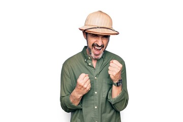 Obraz premium Middle age tourist man on vacation wearing explorer hat over isolated white background celebrating surprised and amazed for success with arms raised and eyes closed