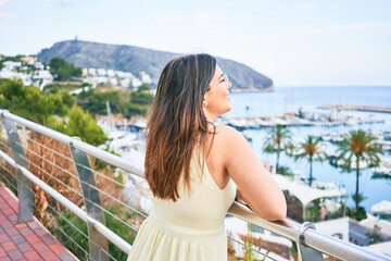 Fototapeta na wymiar Young hispanic woman smiling happy leaning on balustrade looking port landscape