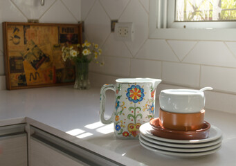 Selective focus of clean ceramic dishware stacked on modern kitchen countertop.