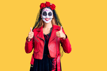 Woman wearing day of the dead costume over background success sign doing positive gesture with hand, thumbs up smiling and happy. cheerful expression and winner gesture.